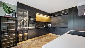 Een moderne keuken met inbouwapparatuur, een wijnkoeler en een visgraat parketvloer.