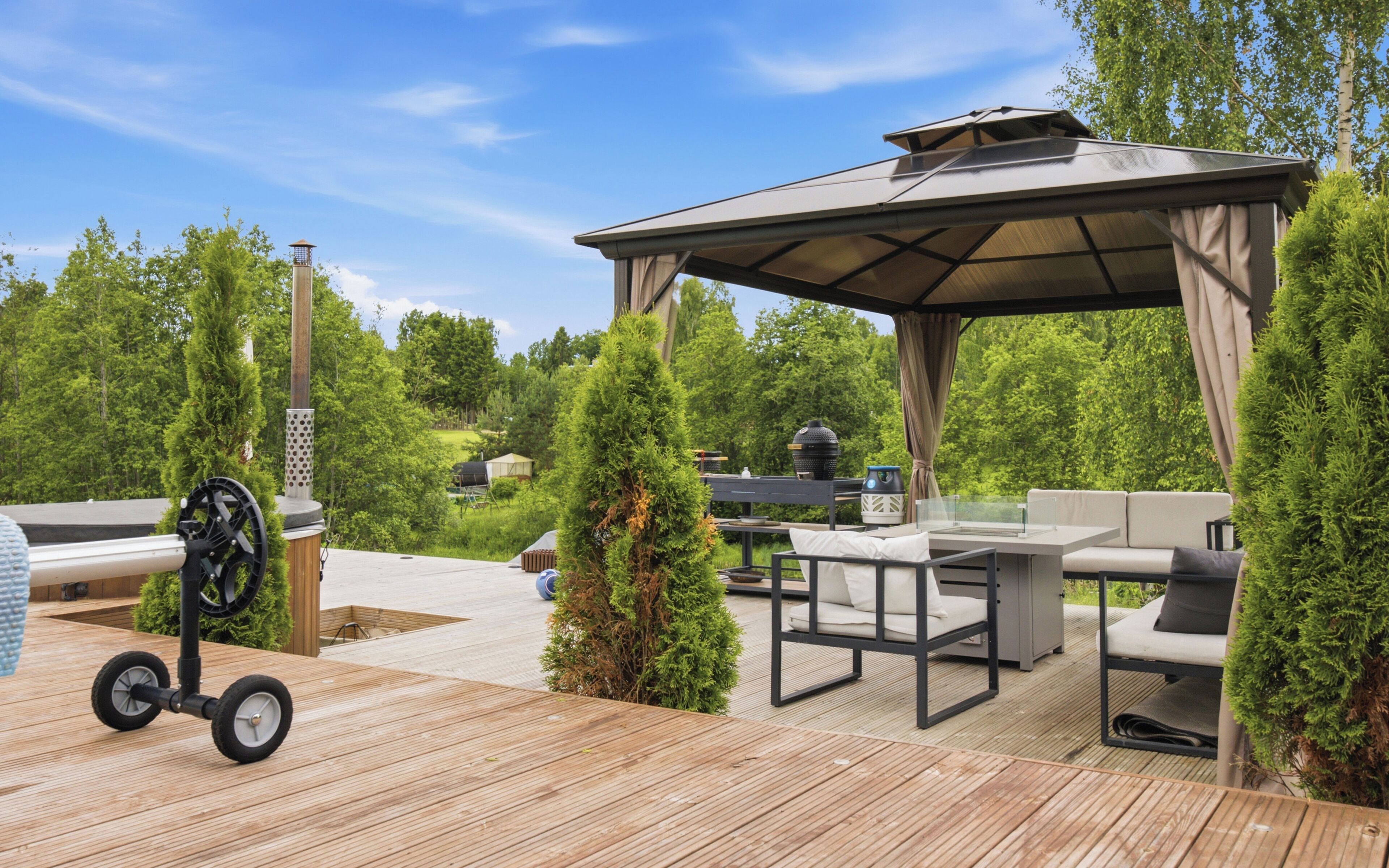 En udendørs terrasse med en pergola, siddeplads og grill.