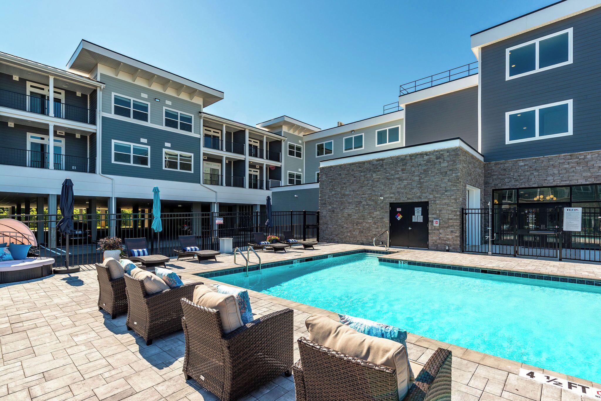 A swimming pool area with lounge chairs and a stone building.