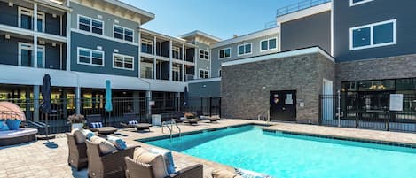 A swimming pool area with lounge chairs and a stone building.