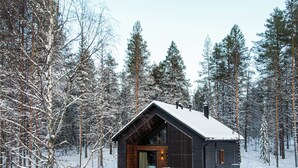 A cabin with a sloped roof, wooden exterior, and a large glass door entrance. - Skýra Retreat (Rovaniemi)