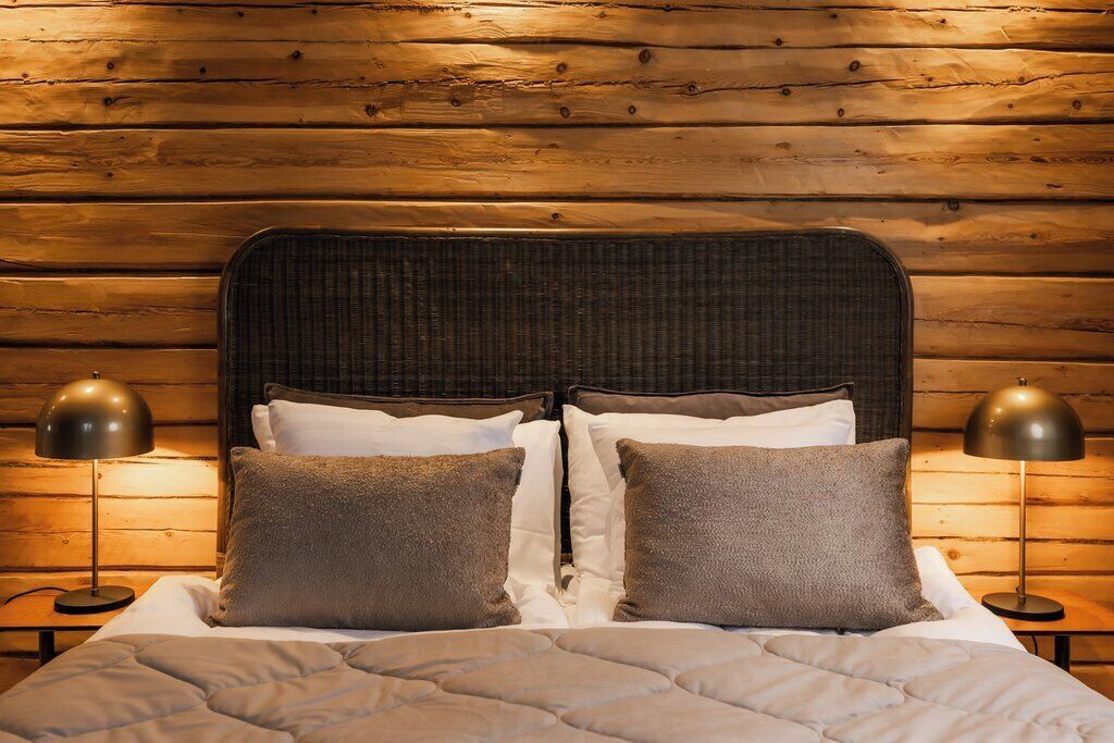 A bed with a dark headboard, white bedding, and two lamps on either side.