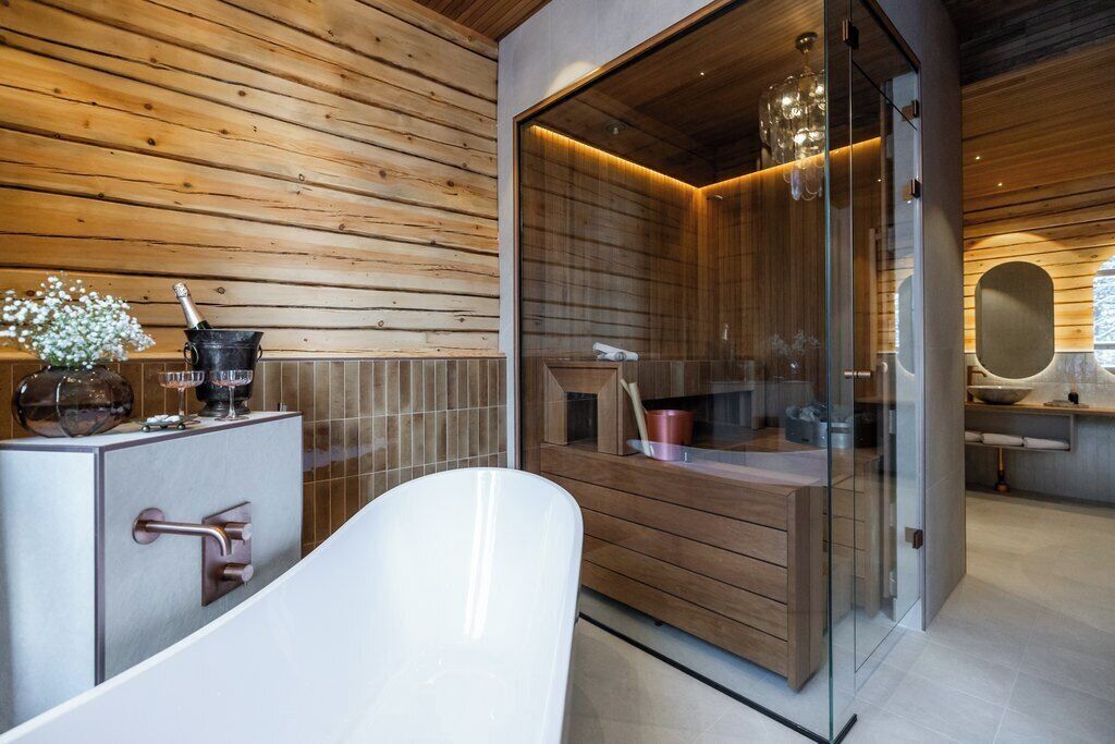 A modern bathroom with a freestanding bathtub, wooden paneling, and a glass-enclosed shower area.