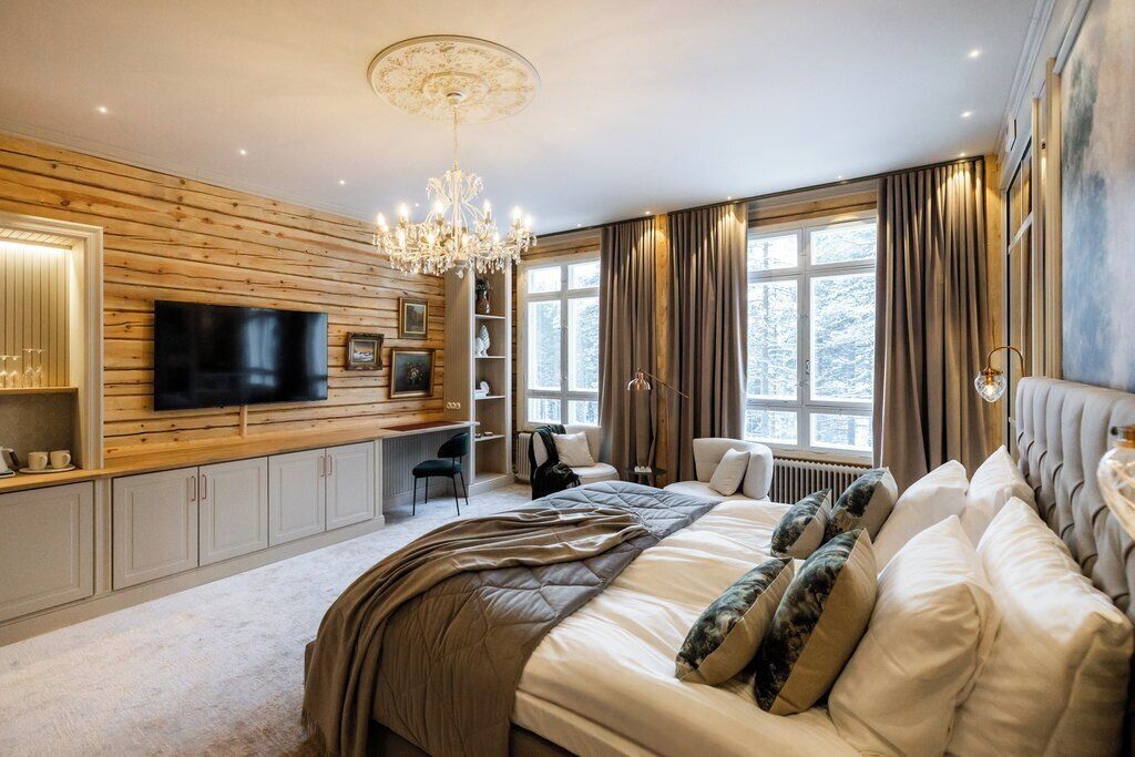 A modern bedroom with a large bed, a television, and a chandelier.