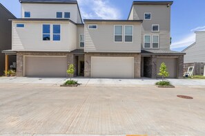 A modern two-story residential building with two garage doors, a brick facade, and a clear sky. - 7 Bedrooms 6 Baths and more! (Lafayette)