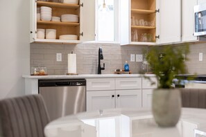 A modern kitchen with white cabinets, a dishwasher, and a dining area with a glass table. - 7 Bedrooms 6 Baths and more! (Lafayette)
