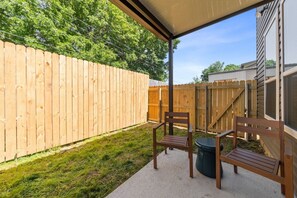 A covered patio area with a wooden fence, a chair, and a trash can. - 7 Bedrooms 6 Baths and more! (Lafayette)