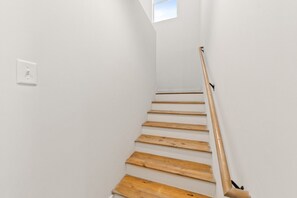 A staircase with wooden steps and a handrail, leading to a landing with a light switch. - 7 Bedrooms 6 Baths and more! (Lafayette)