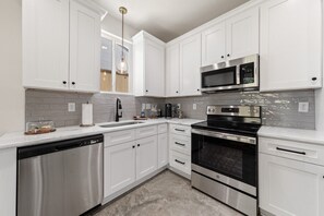 A modern kitchen with white cabinetry, stainless steel appliances, and a marble countertop. - 7 Bedrooms 6 Baths and more! (Lafayette)