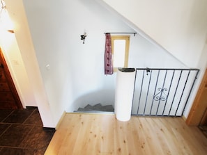 A wooden staircase with a metal railing, a white wall, and a red patterned curtain. - Apartment Tauschna mit Privat-Pool by Interhome (Samedan)