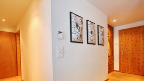 A hallway with wooden flooring, white walls, and three framed artworks.