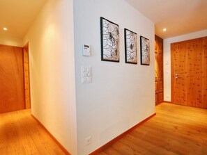 Un couloir doté d’un plancher en bois, de murs blancs et de trois œuvres d’art encadrées.