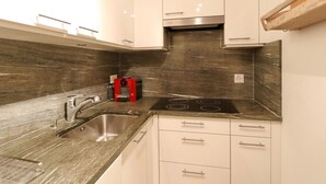 A modern kitchen with a stainless steel sink, a red coffee machine, and a black stovetop.