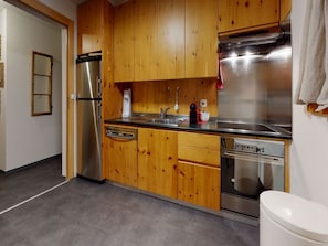 Una cocina con gabinetes de madera, electrodomésticos de acero inoxidable, lavavajillas y pileta.