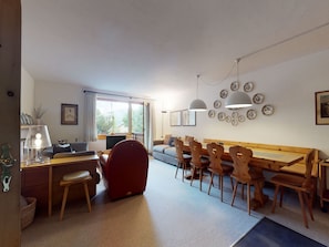 Una sala moderna con sofá, mesa de comedor, sillas y un sillón rojo.