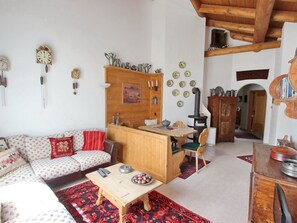 Un salon confortable avec un canapé, une table en bois, un coin cuisine équipé d’une cuisinière et une table à manger avec des chaises.