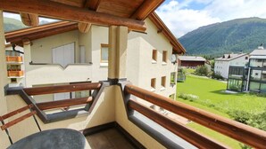 Ein Balkon mit Holzbalkon, einem Tisch und Blick auf eine Berglandschaft.