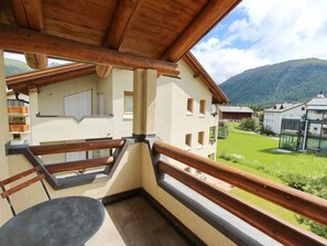 A balcony with a wooden railing, a table, and a view of a mountain landscape. - Apartment Cign OG by Interhome (Celerina)