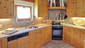 Eine Küche mit Holzausstattung, einem eingebauten Backofen, einer Spüle und einem Fenster.
