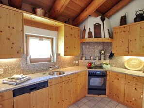 A kitchen with wooden cabinets, a built-in oven, a sink, and a window. - Apartment Cign OG by Interhome (Celerina)