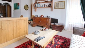 Ein gemütliches Wohnzimmer mit einem Holzkabinett, einem Fernseher und einem Bücherregal voller Bücher.