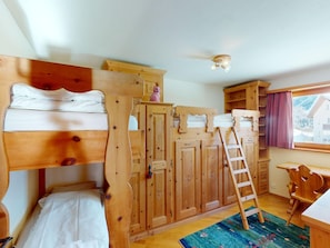 Ein Zimmer mit einem Holzbett mit zwei Etagen, einem Schreibtisch und einem Fenster.