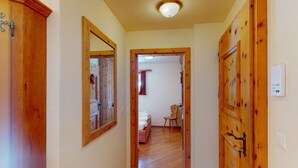 A hallway with wooden doors, a mirror, and a ceiling light. - Apartment Ambretta OG by Interhome (St. Moritz)