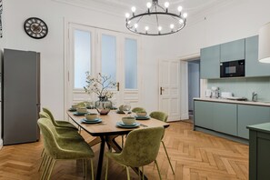 A modern kitchen with a dining area, featuring a chandelier, a refrigerator, and a microwave. - Prime Living Apartment, 135 m², City Center, 2 Bathrooms, Sleeps 8 (Berlin)