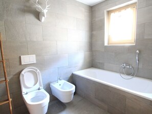 A bathroom with a bathtub, a toilet, and a bidet. - Apartment Diala by Interhome (Zuoz)