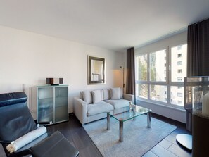 A modern living room with a sofa, a glass coffee table, and a leather chair. - Apartment Braschunauns 10 by Interhome (St. Moritz)