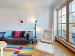 Una sala de estar moderna con sofá, sillón y una alfombra colorida.