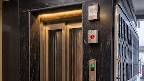An elevator with a digital display, a security keypad, and a door with a metallic finish. - Fortune Home Service Apartment E120 3BHK (Delhi)