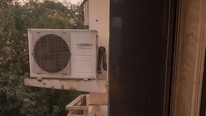 A narrow balcony with a white air conditioning unit and a door leading to an interior space. - Fortune Home Service Apartment E120 3BHK (Delhi)