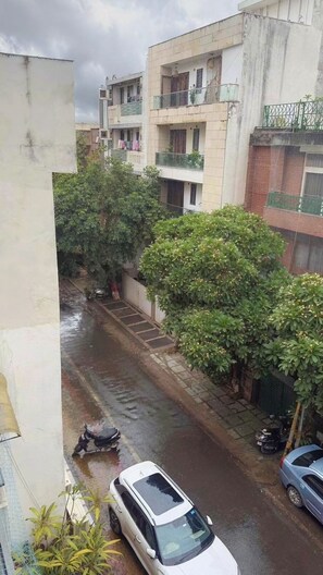 Calle residencial con edificios, pavimento mojado y vehículos estacionados.