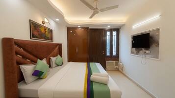A bedroom with a bed, pillows, a ceiling fan, a TV, and a door.