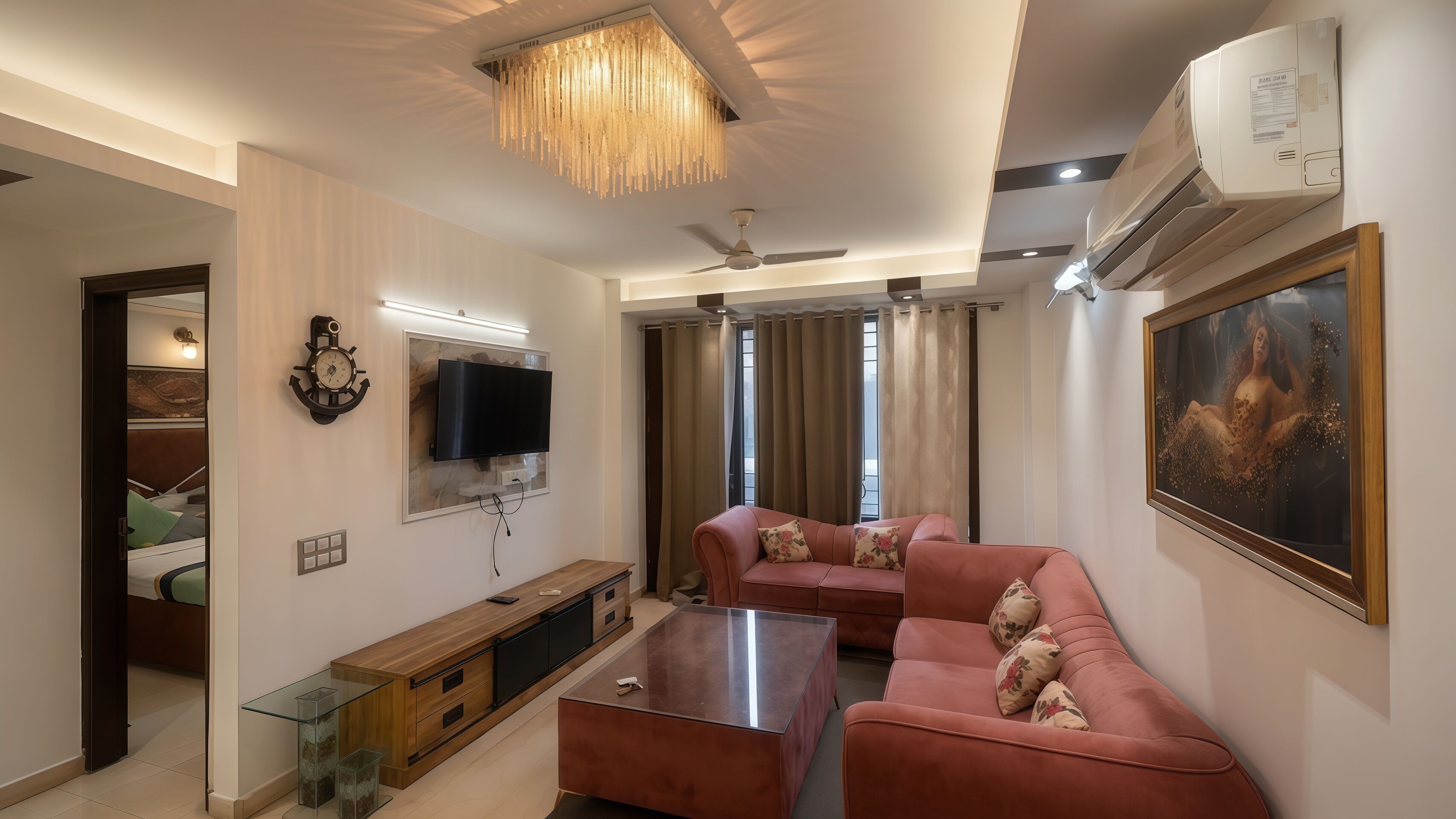 A modern living room with a flat-screen TV, a ceiling fan, a large window with curtains, and a mounted artwork.