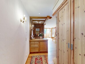 A hallway with wooden cabinets, a rug, and a wooden door. - Apartment Calimera by Interhome (Pontresina)