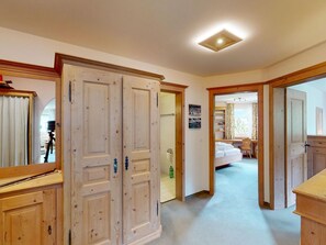 Ein Flur mit Holztüren, ein Bett und ein Schreibtisch im anliegenden Zimmer.
