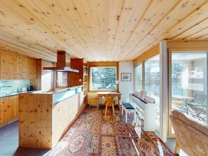 A wooden interior with a kitchen, dining area, and a piano. - Apartment Chalcherin 4 by Interhome (Celerina)