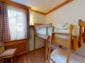 A bunk bed room with a window, a chair, and a lamp. - Apartment Muntagna Alva EG by Interhome (St. Moritz)