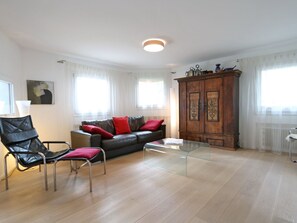 A living room with a leather sofa, a glass coffee table, a wooden cabinet, and a black chair. - Apartment Falcun by Interhome (Celerina)