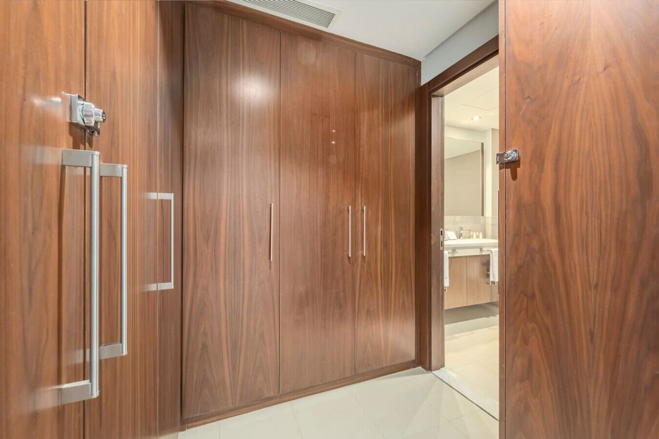 Une armoire en bois dotée d’une porte-miroir, d’une poignée en métal et d’un mécanisme de porte coulissante.