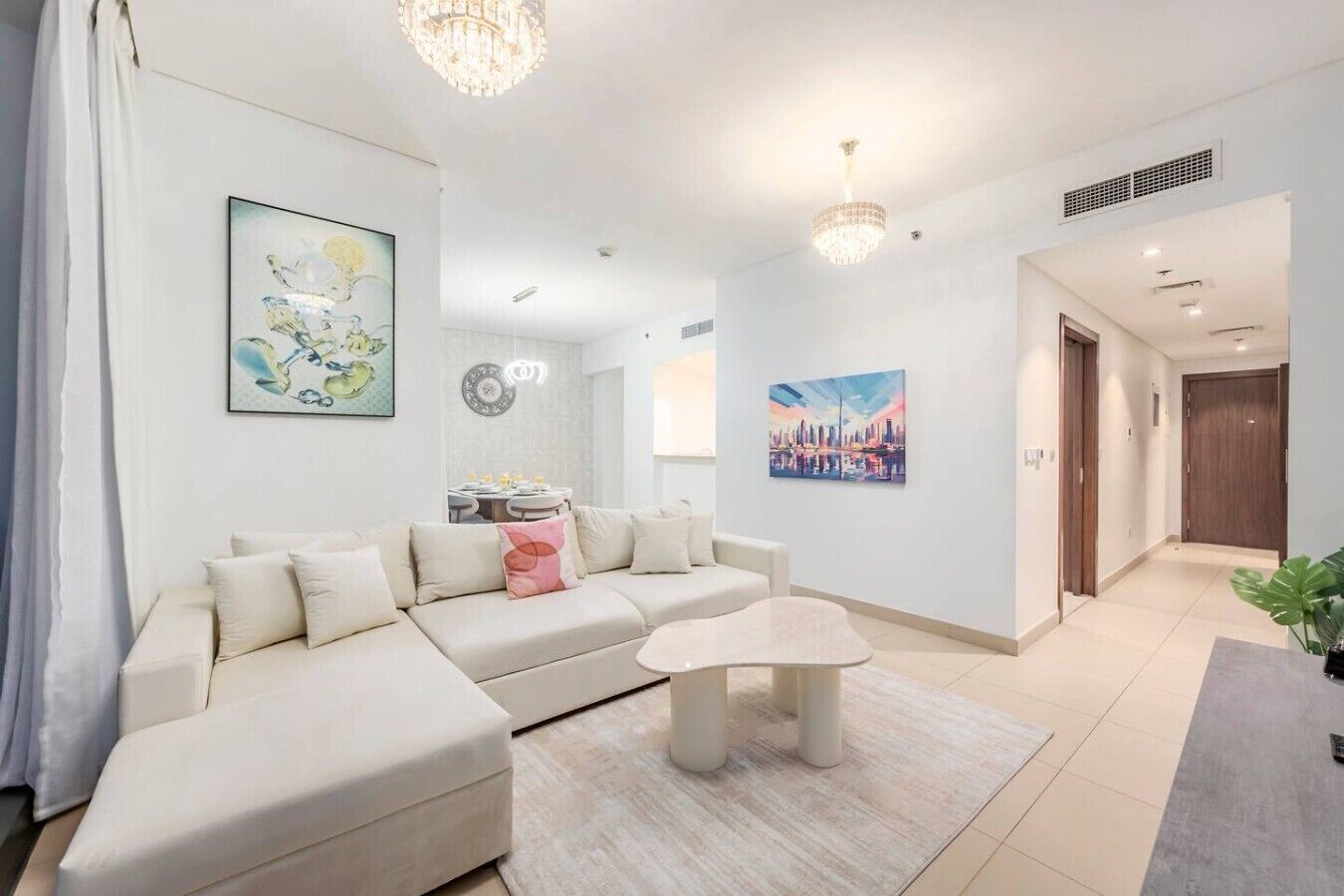 A modern living room with a sectional sofa, a coffee table, and artwork on the walls.