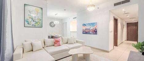 A modern living room with a sectional sofa, a coffee table, and artwork on the walls.