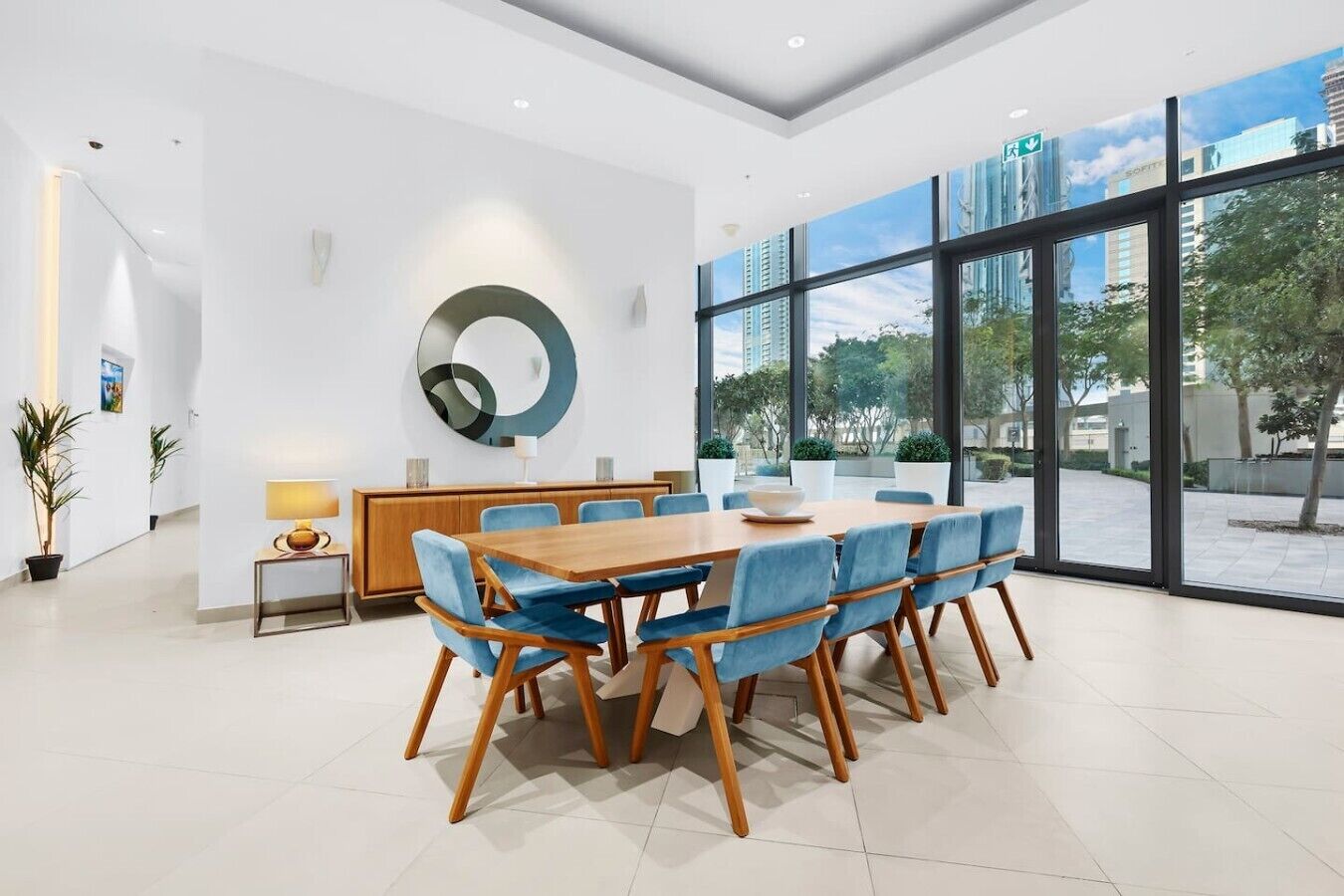 Une salle de conférence moderne, dotée d’une grande table, de chaises bleues et d’une décoration murale circulaire.