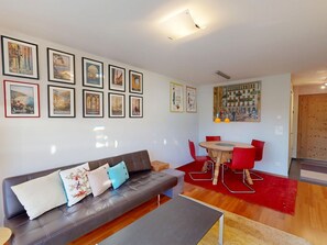 Ein Wohnzimmer mit einer Couch, einem Esstisch mit Stühlen und einem großen Gemälde an der Wand.