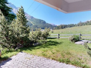 Ein gepflasterter Weg führt zu einem Gebäude mit Blick auf eine Berglandschaft.