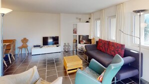 Ein Wohnzimmer mit einer Couch, einem Fernseher und einem Couchtisch.