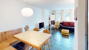 Ein zeitgemäßer Wohnbereich mit Essplatz, einer Couch und einem Fernseher.