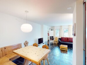 En moderne opholdsstue med spiseplads, sofa og fjernsyn.